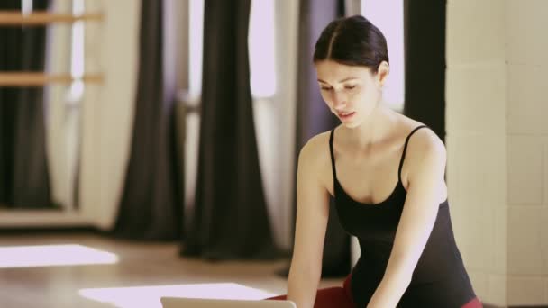 Beautiful girl wearing ballet leotard with laptop — Stock Video