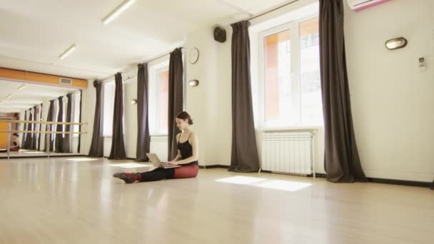 Beautiful girl wearing ballet leotard with laptop — Stock Video