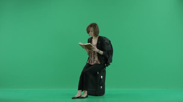 Kvinnlig turist läser sitter på resväskan — Stockvideo