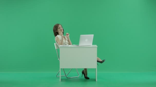 Woman sits by the table with her feet up on desk talking on the phone — Stock Video