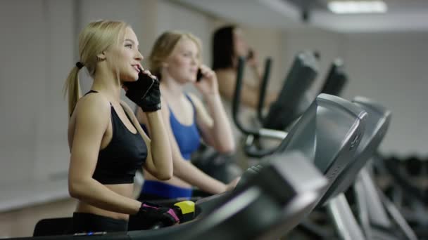 Vrouw lopen op de loopband praten aan de telefoon — Stockvideo