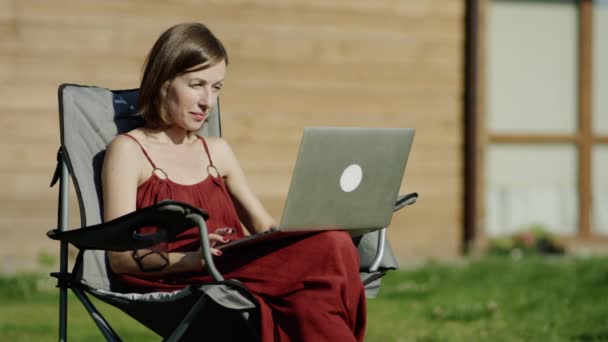 Chica utilizando la tecnología en un prado con portátil — Vídeos de Stock