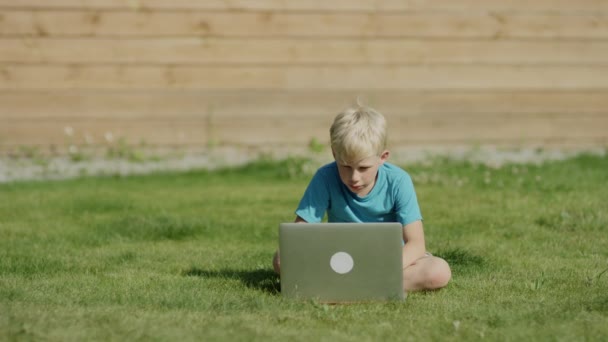 Jongen met laptopcomputer op weide — Stockvideo