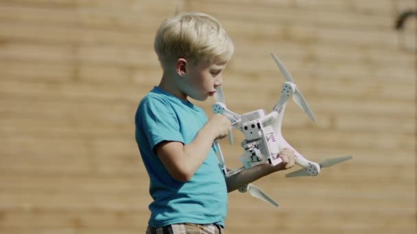 Niño armando un dron moderno en el césped de hierba verde. Montaje de hélices — Vídeos de Stock