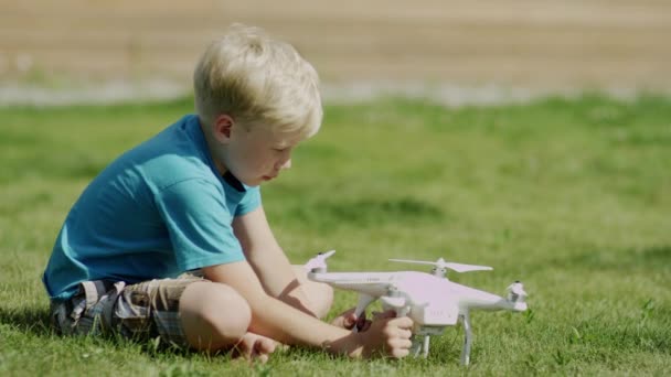 Niño armando un dron moderno en el césped de hierba verde. Montaje de hélices — Vídeos de Stock