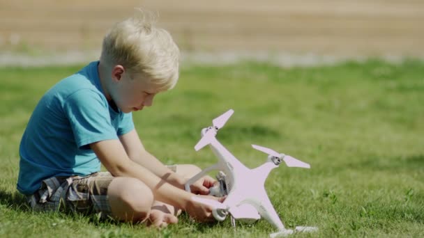 Enfant assemblant drone moderne sur la pelouse d'herbe verte. Mise en marche des hélices — Video