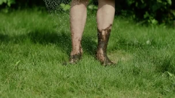 Washing dirty legs with hose — Stock Video