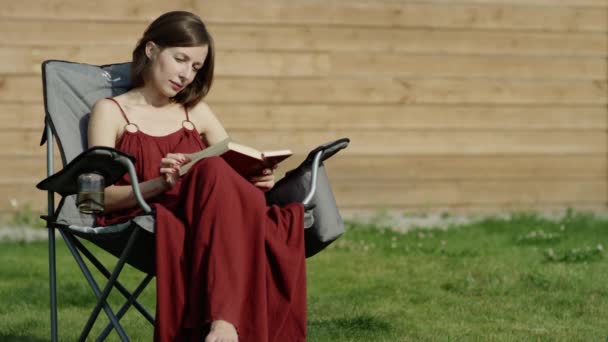 公園、ドリー ショットで木の本を読んで若い魅力的な女性 — ストック動画