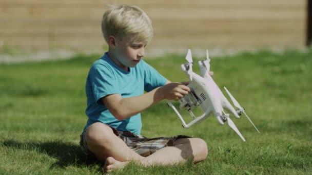 Niño armando un dron moderno en el césped de hierba verde. Montaje de hélices — Vídeo de stock