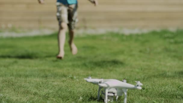 Niño armando un dron moderno en el césped de hierba verde. Montaje de hélices — Vídeos de Stock