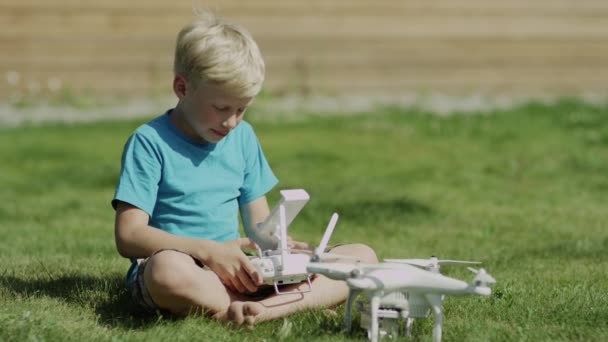 Niño armando un dron moderno en el césped de hierba verde. Montaje de hélices — Vídeos de Stock