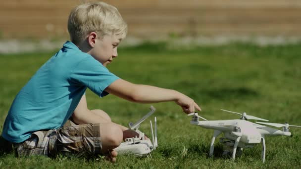 Kind montiert moderne Drohne auf dem grünen Rasen. Propeller anlegen — Stockvideo