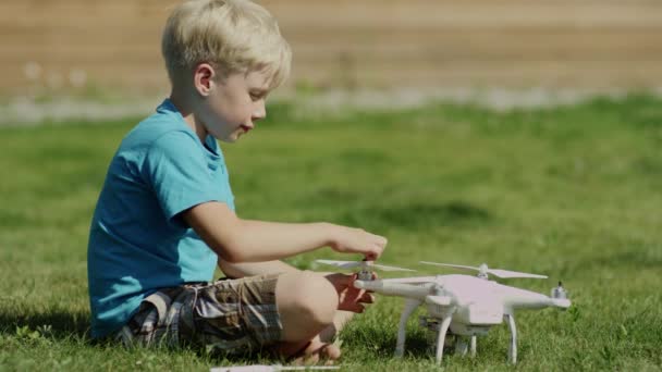녹색 잔디 잔디밭에 현대 무인 항공기를 조립 하는 아이. 프로 펠 러에 — 비디오