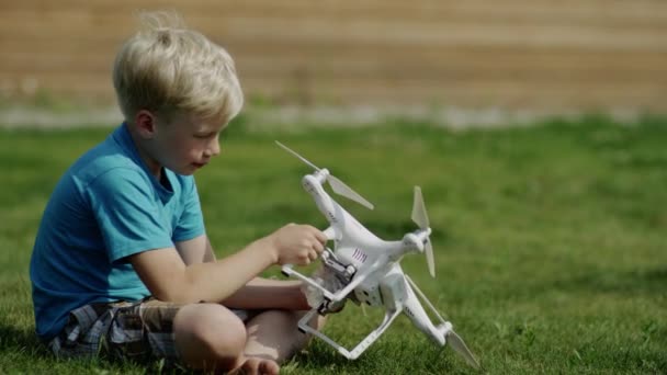 Niño armando un dron moderno en el césped de hierba verde. Montaje de hélices — Vídeos de Stock