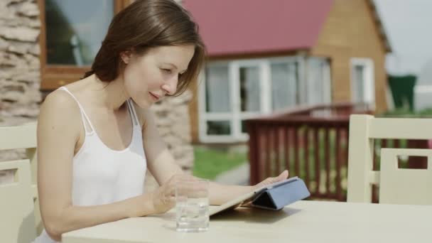 Χαριτωμένο νεαρή γυναίκα με το tablet στο πάρκο, φοιτήτριας νέων κάθεται σε ένα παγκάκι στο πάρκο και χρησιμοποιώντας ένα tablet — Αρχείο Βίντεο