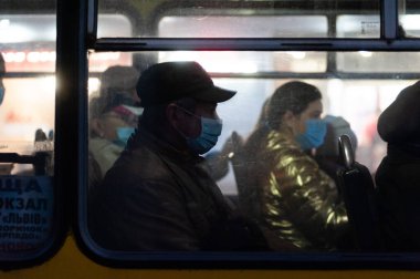 Lviv, Ukrayna, 4 Kasım 2020. Koronavirüsün önleyici önlemi olarak yüz maskesi takan insanlar toplu taşımada otururlar.. 