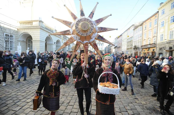 Lviv, Ukrayna 6 Ocak 2021. Ukraynalılar Beytüllahim 'in süslü yıldızlarını ve buğday demetlerini taşırken Noel şarkıları söylüyorlar. Eski Julian takvimine göre Ukraynalı inananlar Ortodoks Noel Gününü 07 Ocak 'ta kutladılar.