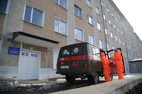 24 Şubat 2021. Bohorodchany, Ukrayna. Koruyucu giysiler giyen sağlık çalışanları COVID-19 'dan muzdarip yaşlı bir kadının hastaneye gitmek için ambulanstan inmesine yardım ediyor..