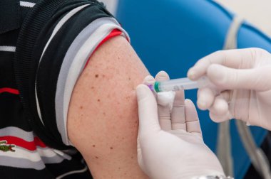 Lviv, Ukraine 23 June 2021. A healthcare worker applies  a dose of Coronavac vaccine to a man. clipart