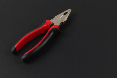 Siyah bir yüzey üzerinde bir kerpeten seti duruyor. Araç, kavrama ve kesme gibi çeşitli görevler için ideal kırmızı ve siyah kauçuk kavrama özellikleri.