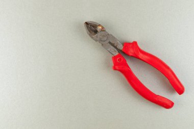 Kırmızı kablo kesiciler açık gri bir yüzeyde duruyor ve dayanıklı tasarımlarını sergiliyorlar. Kabloları kesmek ve evde çeşitli onarım işleri yapmak için ideal.