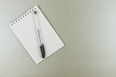Izgara dizaynlı bir not düz gri bir yüzey üzerinde siyah bir kalem yanında oturur, çalışma ya da planlama oturumları sırasında düşünce ve fikirlere hazır.