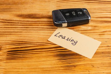 Kiralama yazan bir notun yanında bir araba anahtarı ahşap bir masanın üzerinde duruyor. Odunun sıcak tonları, anahtarın metalik bitişiyle tezat oluşturuyor..