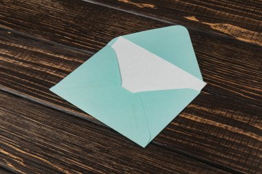Parlak yeşil bir zarf kırsal bir ahşap masanın üzerinde, doğal ışıkla aydınlatılmış bir şekilde duruyor. Bu da içeride bir mektup ya da kart beklediğini gösteriyor..