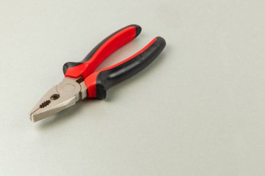 Rahat kırmızı ve siyah kabzalı pense pürüzsüz bir ışık yüzeyine yerleştirilir. Çalışma alanındaki çeşitli onarım ve DIY görevleri için idealdir..