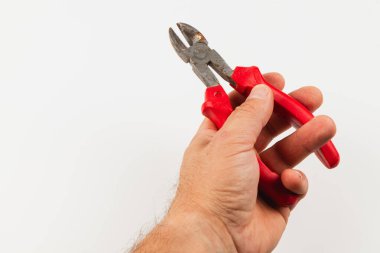 Bir el, ev onarımı ve el işi için kullanılan kırmızı kablo kesicileri kavrıyor. Bir DIY projesi sırasında kablolar veya küçük malzemeler kesmek için araç hazırdır.