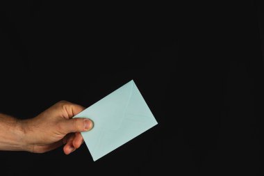 Bir el, açık mavi bir zarf tutarak izleyiciye doğru uzanır. Kapkara arka plan zarfın altını çiziyor. İletişim temalarını ifade etmek için ideal.