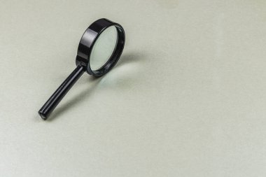 Parlak, siyah bir büyüteç nötr gri bir yüzeye dayanır, tasarımı ve yapısı vurgulanır. Cam mercek ışığı incelikle yansıtır, zarif bir görünüm yaratır..