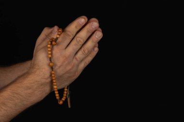 Kapalı ellerde ahşap bir tespih vardır. Karanlık bir arkaplanda yakılan duanın dinginliğini ve yansımasını sembolize eder..