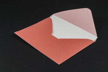 Açık bir zarf, mercanların canlı bir dış görünüşünü ve yumuşak beyaz bir astarı gösteriyor. Koyu arkaplan, zarfın renklerini ve dokularını güzel çiziyor..