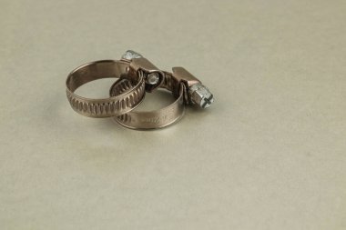 İki metal kıskaç pürüzsüz, açık renkli bir yüzeye yerleştirilir. Bunlar çeşitli ev geliştirme görevlerinde hortum veya boruları güvence altına almak için kullanılır..