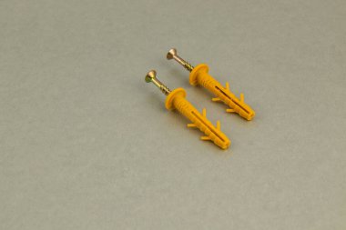 İki turuncu inşaat işleyicisi düz gri bir yüzey üzerinde yan yana oturur. Bu araçlar çeşitli bina projeleri ve onarım için gereklidir.