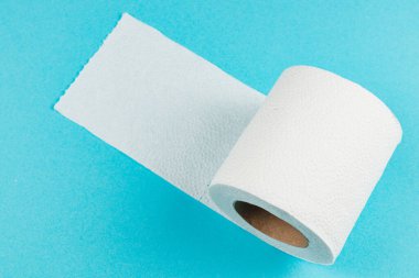 Bir rulo beyaz kağıt havlu parlak mavi bir yüzeye oturur, havlunun bir kısmı açılır ve yavaşça aşağı akar. Olay yeri temiz ve basit bir ev eşyasını yakalıyor..