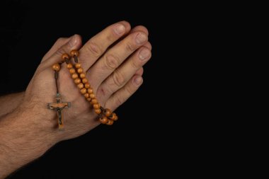 Bir çift el, haçla ahşap bir tespihi tutuyor. Karanlık bir ortamda bağlılık ve dinginliği ifade ediyor. İnancı ve maneviyatı simgeliyor..