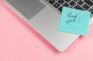 Üzerinde mesaj olan deniz mavisi yapışkan bir not. Aferin! Gümüş bir dizüstü bilgisayarın klavyesinde, parlak pembe bir arkaplan üzerine kurulmuş, destek ve motivasyonu iletiyor..