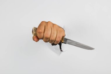 Gerçekçi bir el, beyaz bir duvardaki delikten çıkarken bıçağı kavrar. Sahne şaşırtıcı ve sanatsal bir anı yakalıyor, mizahla gerilimi harmanlıyor..