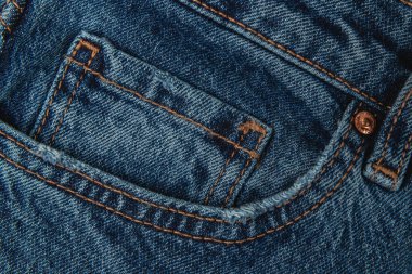 Detailed view of a blue denim jeans pocket, showcasing stitching and fabric texture. Ideal for fashion lovers and those interested in clothing design.
