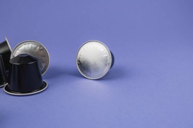 Lviv Ukrayna 12.08.2025 Kahve kapsülleri mor arka planda düzenlenmiştir. Yuvarlak üstler gümüş bir yüzey gösterirken siyah altlar renkli yüzeyde dinleniyor..