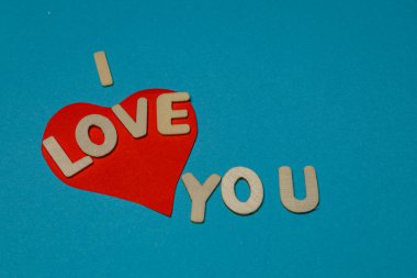 Mavi yüzeyde kırmızı kalp şekli ve seni sevdiğimi belirten mektuplar var. Parlak renkler basit bir sevgi ve neşe gösterisi yaratır..