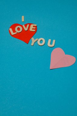 Parlak mektuplar bir aşk mesajı oluşturdu. Kırmızı ve pembe kalpler tasarımın bir parçası. Mavi arkaplan harflerin ve kalplerin rengini arttırır.