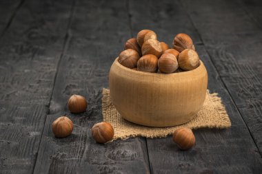 Siyah bir masada, tahta bir kasede büyük fındıklar. Sebze proteinin kaynağı.