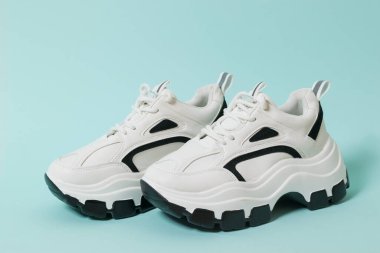 Mavi arka planda siyah eklemli şık beyaz ayakkabılar. Yüksek tabanlı spor ayakkabılar..