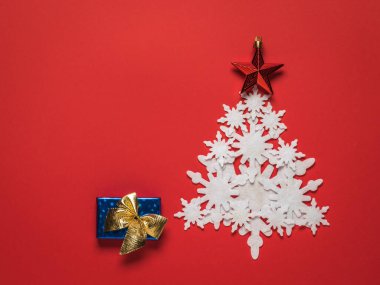 Kağıttan yapılmış Noel ağacı ve kırmızı arka planda bir hediye kutusu..