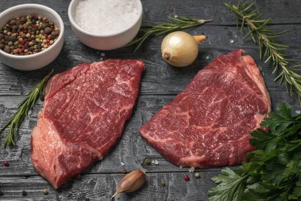 Két marhahús, hagyma és rozmaring egy fa asztalon.. — Stock Fotó