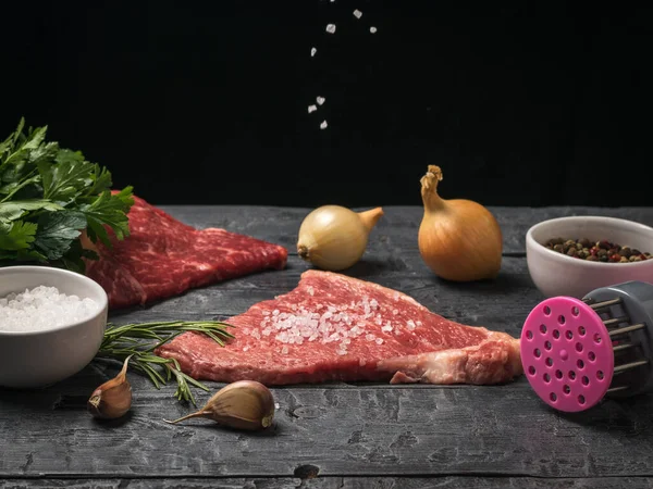 Cristais de sal caem em um pedaço de carne em uma mesa de madeira. — Fotografia de Stock