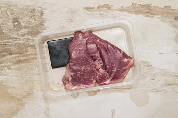 木制底座上装有新鲜牛肉蒸肉的真空包装. — 图库照片